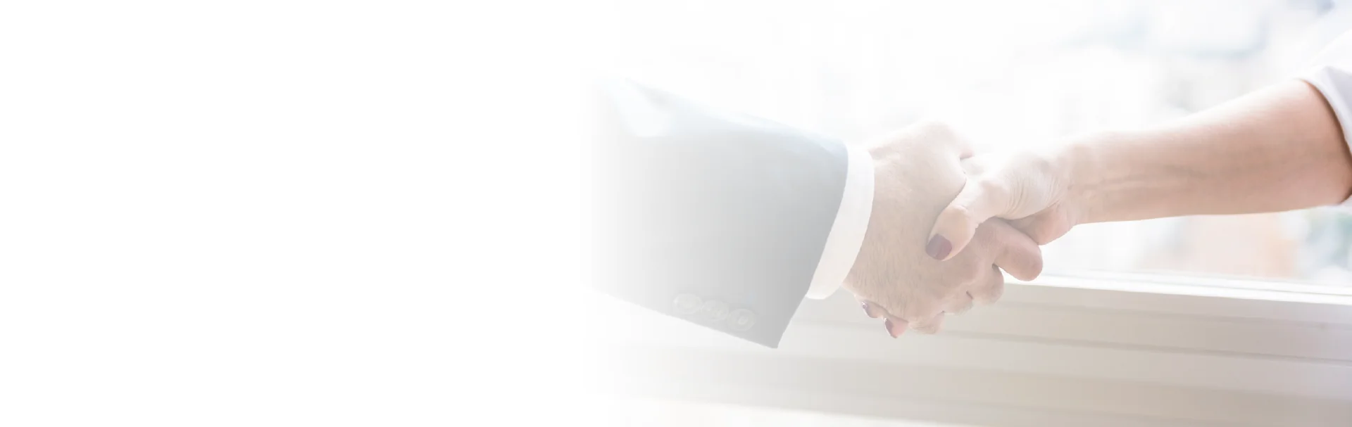 Two individuals shaking hands in front of a window, symbolizing a professional agreement or partnership