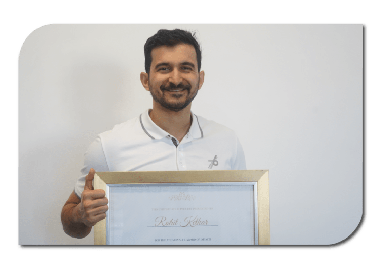 A man proudly holds a framed certificate in front of a white wall